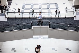 Image of two men walking and talking with each other in a corporate building.