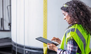 A field service worker in a yellow reflective vest working on a Microsoft tablet.
