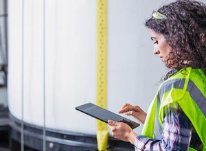 A field service worker in a yellow reflective vest working on a Microsoft tablet.