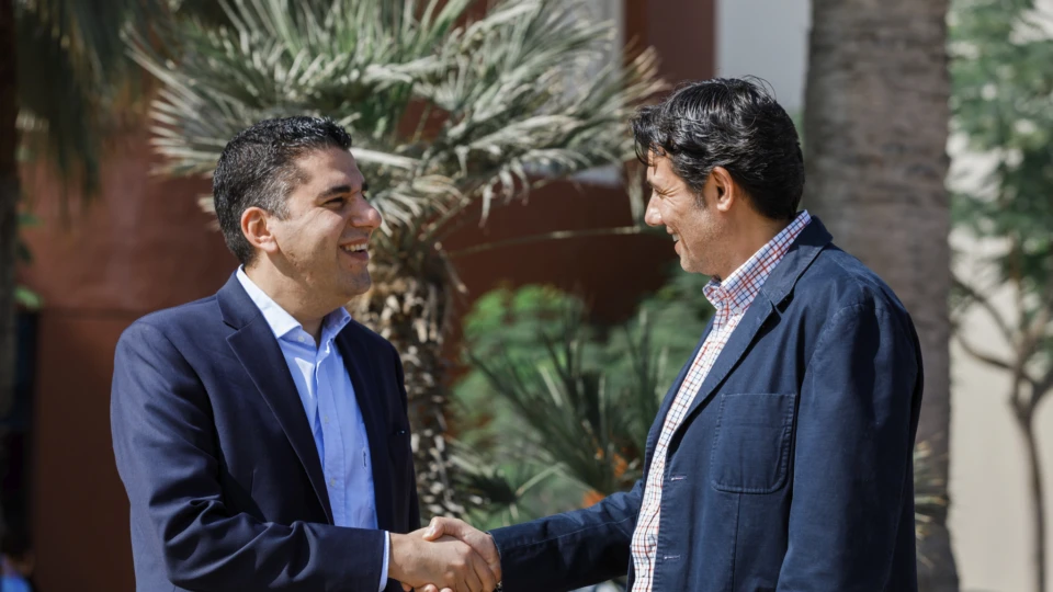 Two business people shaking hands and smiling.