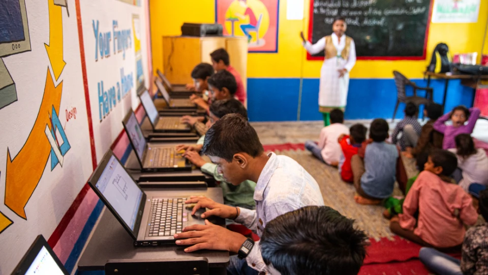 Students learn basic computer skills on laptop computers in classroom of a primary school near Delhi.