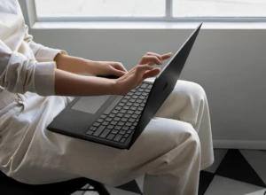 Contextual image of woman touching screen while working on Black Surface Laptop 2