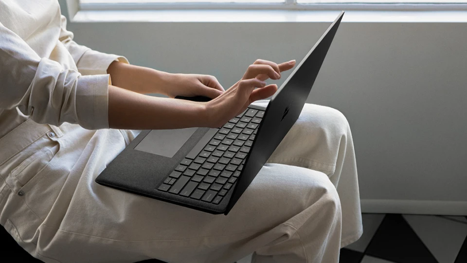 Contextual image of woman touching screen while working on Black Surface Laptop 2