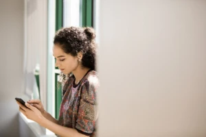 Young, small business female with phone in modern workplace.