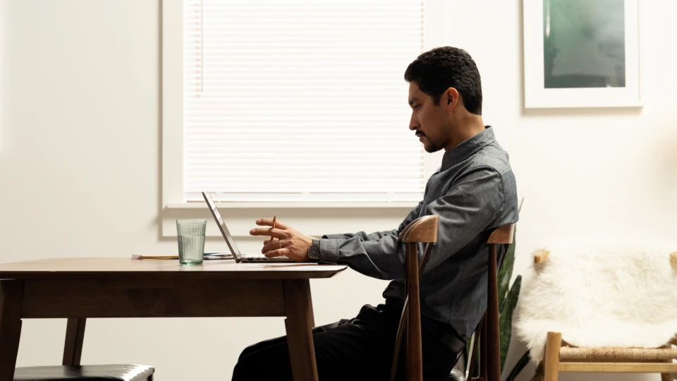 Side photo of man working at the dining room table with a Dell Latitude 7410. Keywords: remote work, remote working, work from home, working at home, home office, telecommuting, video conference, video call