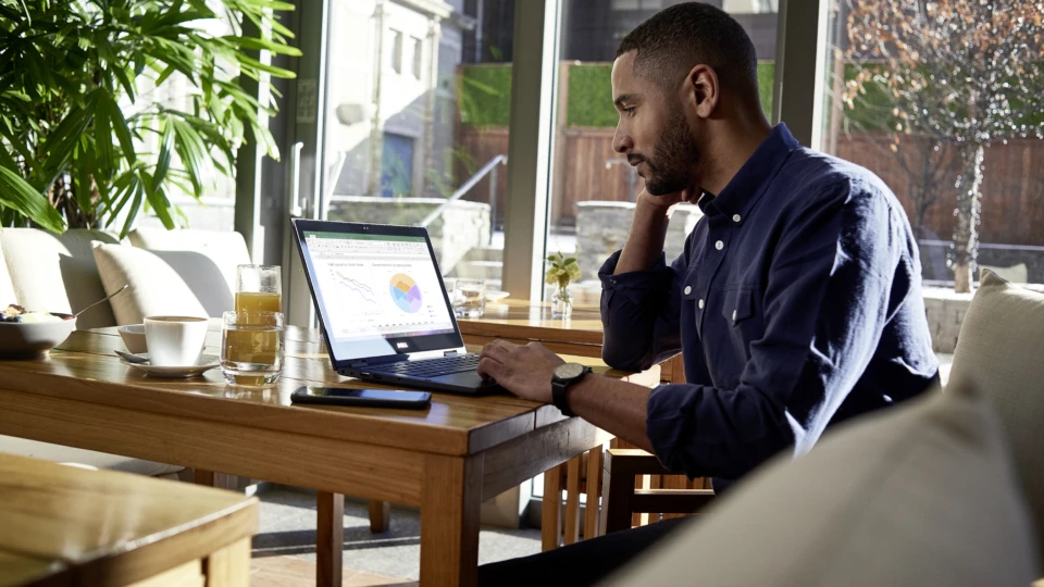 Male business professional at breakfast on a Dell device running Microsoft Excel