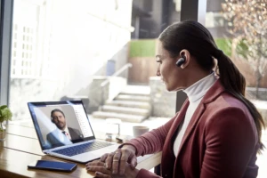 Female small business executive using HP Elite device on Microsoft Teams; bluetooth; coffee.