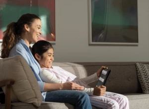 A mother and her daugther reading a webpage with Immersive Reader in Microsoft Edge. The Acer Travelmate B311 2-in-1 is in tablet mode. Remote Learning collection. Keywords: remote education, remote learning, home school, study from home