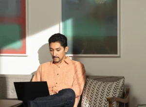 A man sitting on his living room couch working on a Lenovo ThinkPad X1 Carbon. Remote Working collection. Keywords: remote work, remote working, work from home, working at home, home office