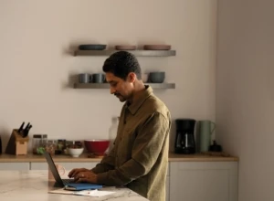 A man working from the kitchen during the day with a Lenovo ThinkPad X1 Yoga. Keywords: remote work, remote working, work from home, working at home, home office