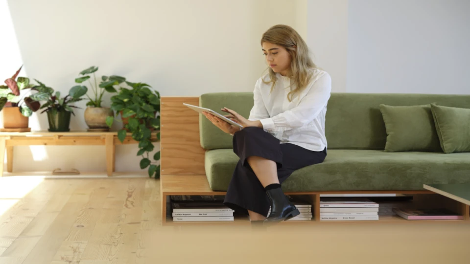 A female architect sitting on a green couch using a Surface tablet.