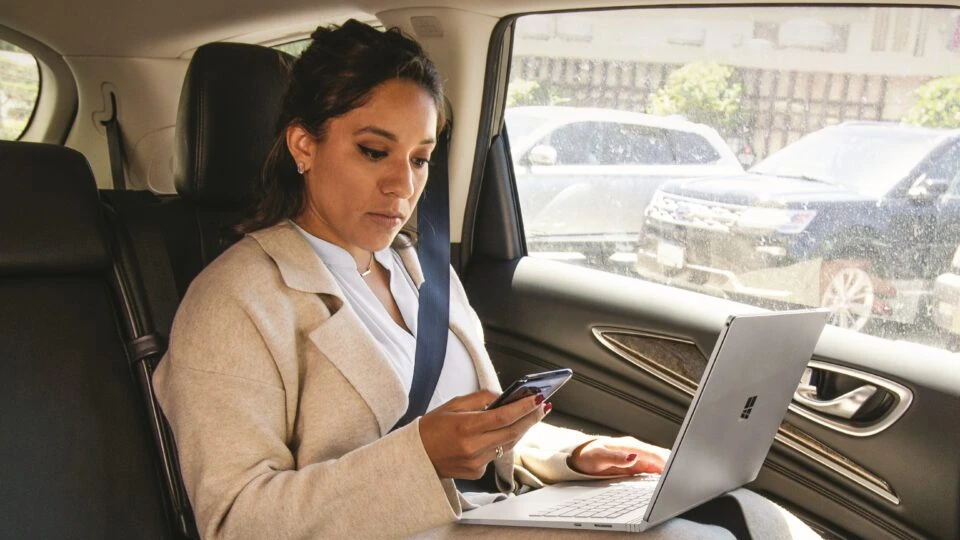 A sales manager in the car with a laptop.