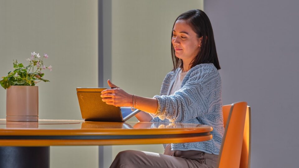 Business person closing Lenovo ThinkPad X1 Fold while sitting at a conference room table.