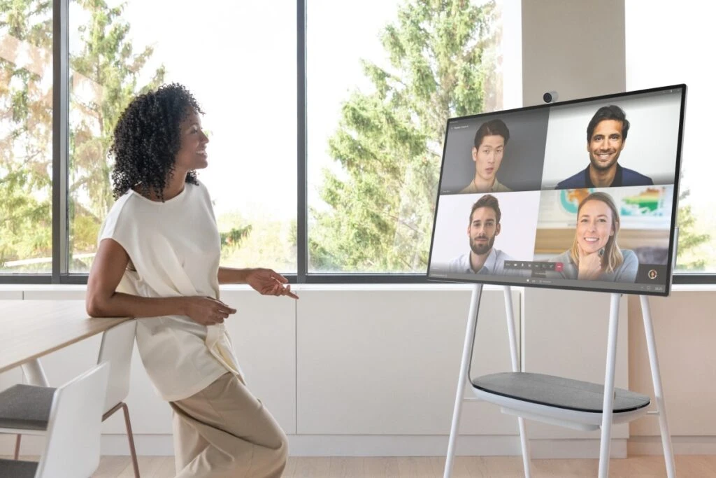 A person in an office along engaging with a Microsoft Teams calls with four faces on video.