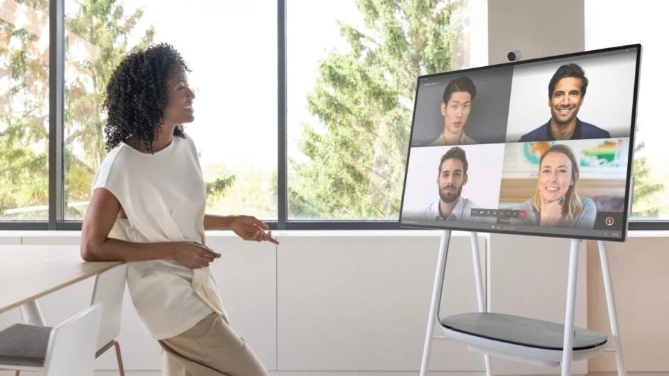 A person in an office along engaging with a Microsoft Teams calls with four faces on video.