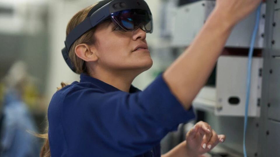 Field engineer inspects electrical substation server room on a wind farm using remote assist with HoloLens2. Keywords: Dynamics 365; operations; woman; green energy; remote training