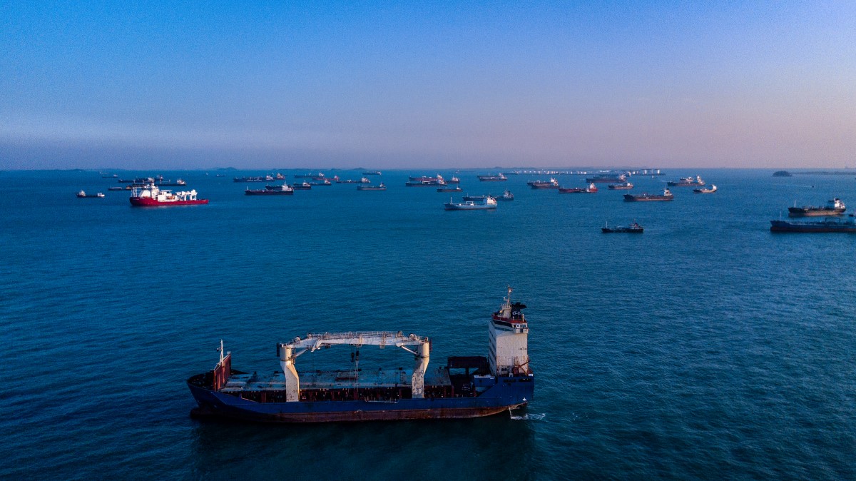 Aerial view of cargo ships waiting offshore to dock in Singapore harbor.