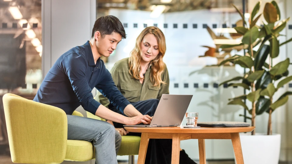Man and women interacting with a Lenovo Yoga laptop.