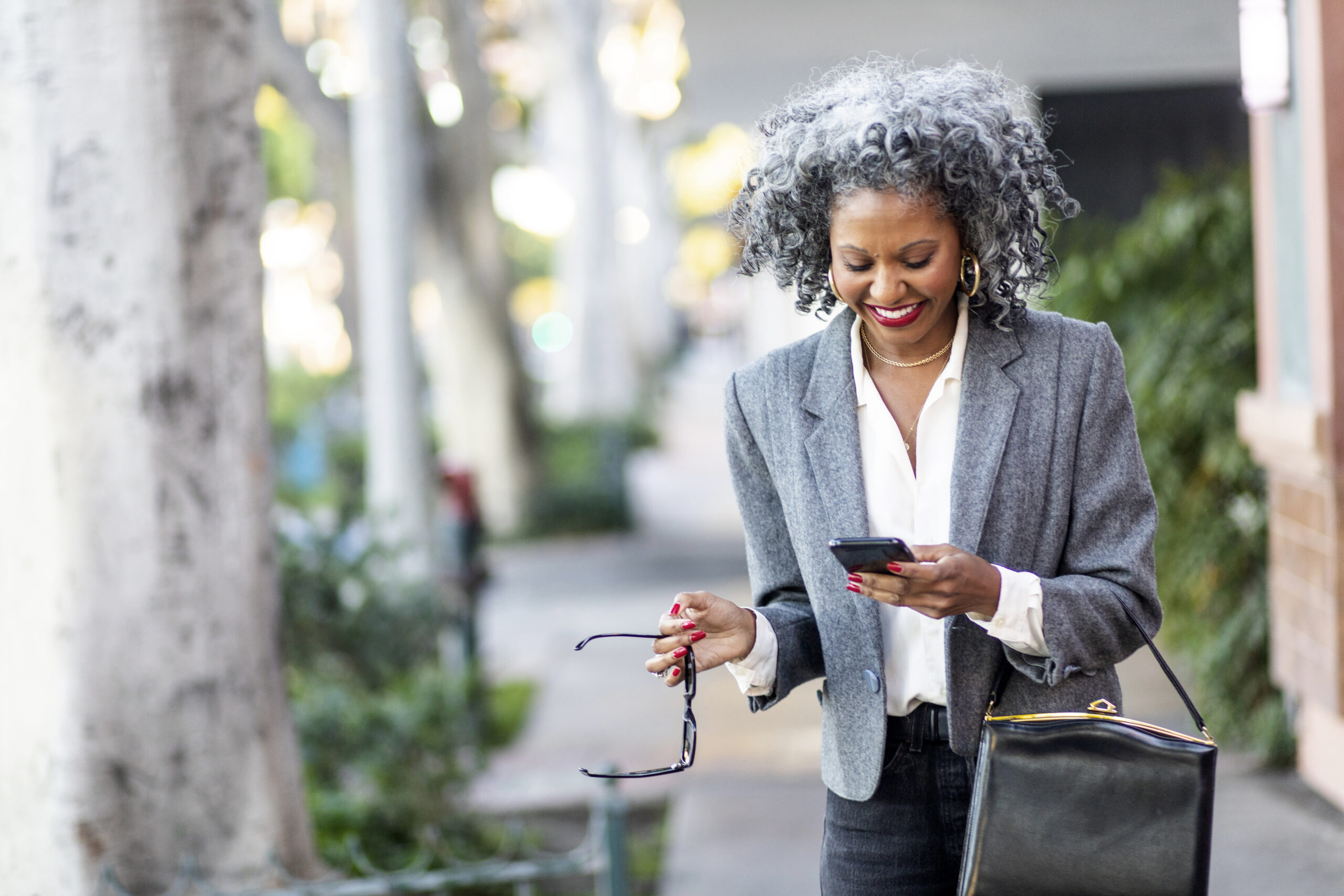 Photo of a smiling Black woman texting a support agent.