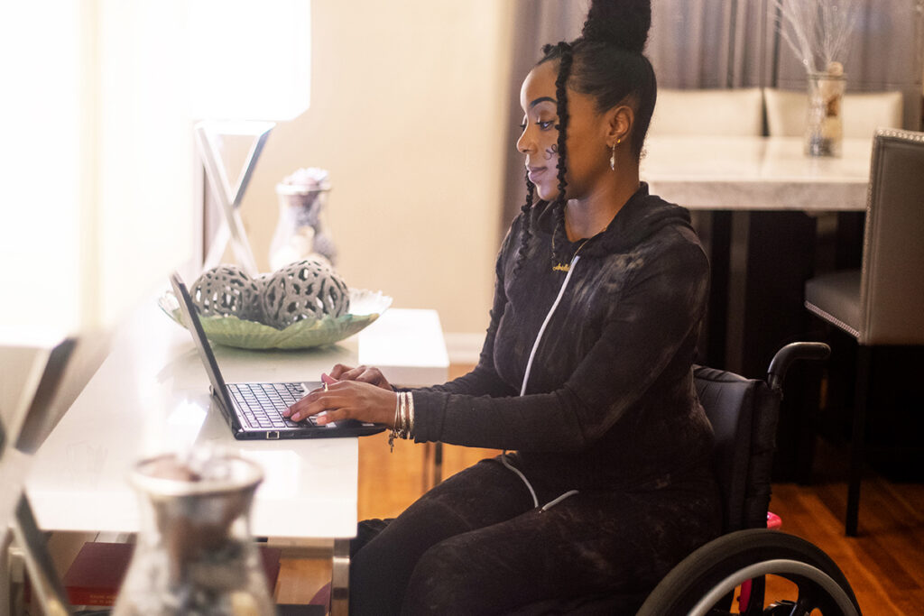 Woman in wheelchair working on a laptop at a desk