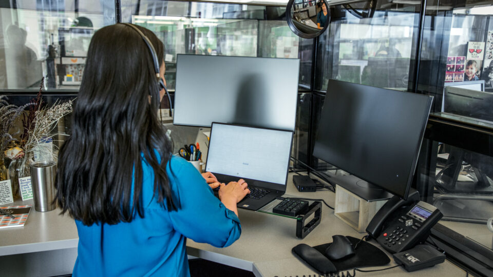 Photo of a female call center employee working at a standing desk.