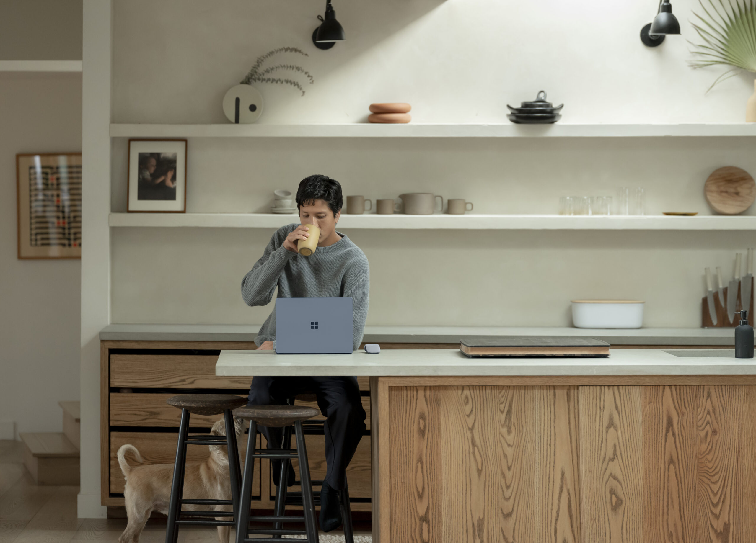 Photo of a man working on a laptop in a kitchen.
