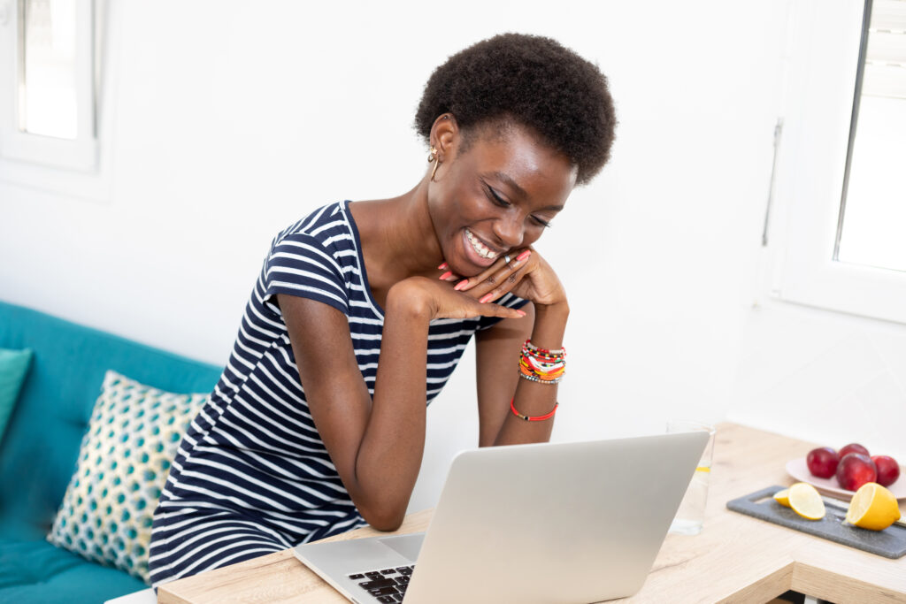 Photo of a young woman smiling at a laptop while reading a marketing email with personalized content.