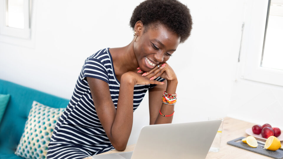 Photo of a young woman smiling at a laptop while reading a marketing email with personalized content.