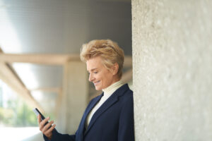 Photo of a happy customer looking at her cell phone on the go.