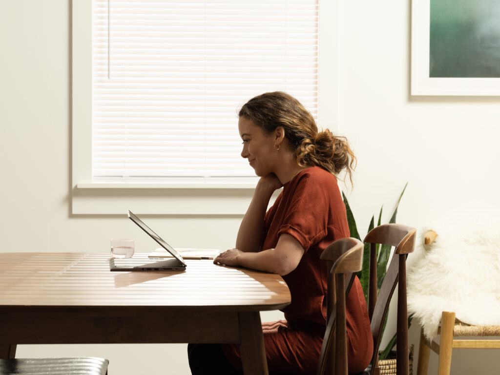 Vista lateral de una mujer trabajando en una mesa en una tableta.