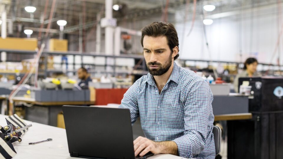 Man sitting at workstation in commercial manufacturing plant.
