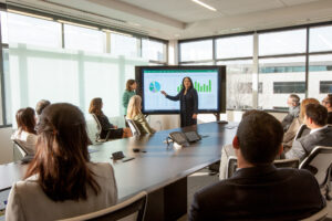 Photo of a group of executives around a conference table, with the CEO pointing to data displayed on a large screen.