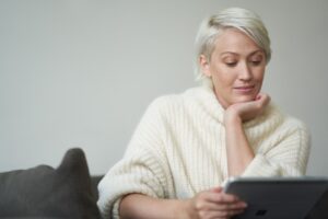 Woman browsing the internet via her tablet while on sitting on a couch.