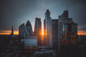 Aerial panoramic view of The City of London cityscape skyline with metropole financial district modern skyscrapers during sunrise with illuminated buildings and cloudy sky in London, UK