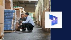 Two employees crouching down by boxes in a warehouse. The image incorporates the Dynamics 365 icon.