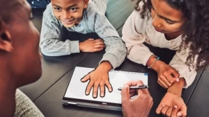 Ein Lehrer und zwei Schüler arbeiten mit einem Surface Pen auf einen Surface Device