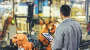 Ein Mechaniker in einer Fabrikhalle hält ein Tablet in der Hand