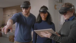 Drei Personen mit einer Microsoft HoloLens 2 schauen sich in einem virtuellen Raum um.