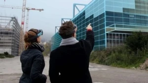 Zwei Menschen schauen mit einer HoloLens auf im Bau befindliche Häuser