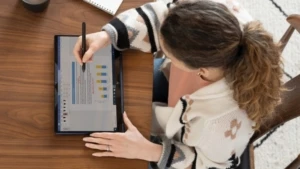 Überkopf-Ansicht einer Frau, die von zu Hause aus an ihrem Esstisch auf einem HP Elite Dragonfly im Tablet-Modus arbeitet und eine Microsoft Word-Datei anzeigt.