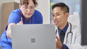 Zwei Angestellte im Gesundheitswesen, eine Frau und ein mann, schauen gemeinsam auf ein Surface Device