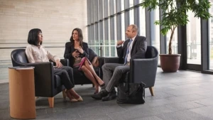 Drei Personen, zwei Frauen und ein Mann , sitzen in einer Büroetage und unterhalten sich