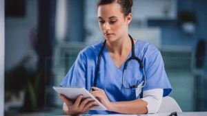 Eine Ärztin im blauen Kittel bei der Arbeit an einen Tablet PC