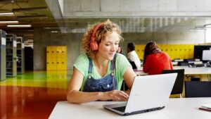 Eine blonde Studentin sitzt an einem Tisch und arbeitet mit einem Acer Device