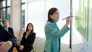 Alternative Text for the above images People in business attire going over numbers in a meeting using the Surface Hub.