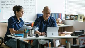 Woman and man sitting at an office desk looking at a Surface Pro