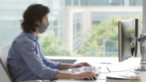 man wearing a mask working on his computer