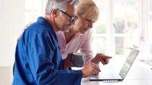 elderly couple examining something on the laptop screen together