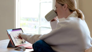 woman sipping from a mug working on her Surface Pro