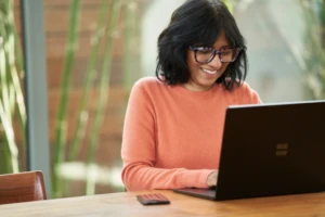 Woman wearing glasses while typing on a laptop.